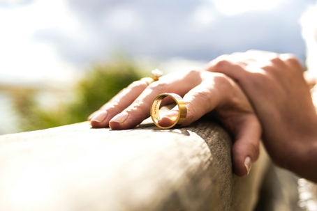 Divorcee holding wedding ring on ledge