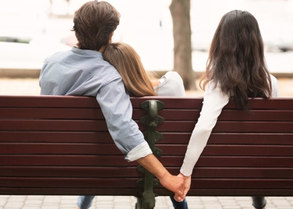 man holding hands with woman on bench
