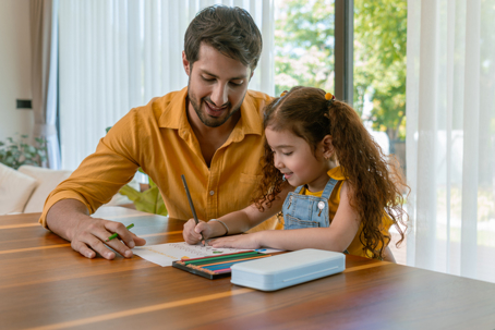 father helping daughter with coloring book